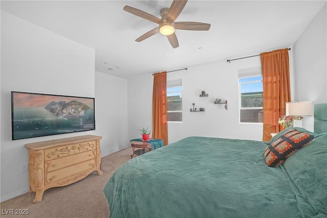 bedroom featuring light colored carpet, baseboards, and a ceiling fan