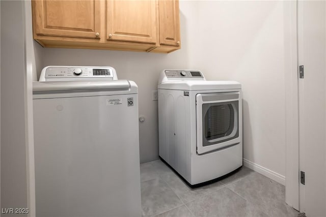 laundry area with cabinet space, light tile patterned floors, independent washer and dryer, and baseboards