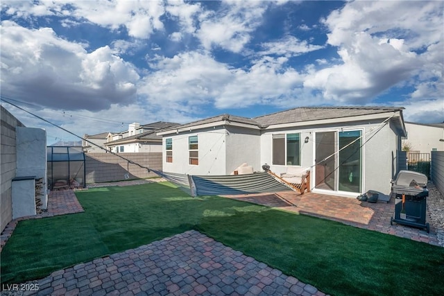 rear view of house featuring a yard, a patio area, a fenced backyard, and stucco siding