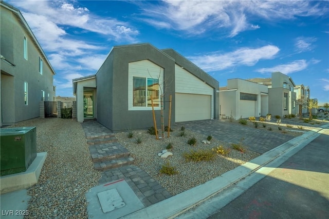 view of front facade featuring decorative driveway, an attached garage, and stucco siding