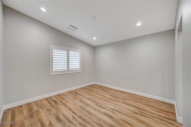 unfurnished room with lofted ceiling, light wood-style flooring, visible vents, and baseboards