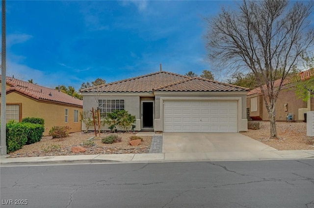 view of front of house featuring concrete driveway, an attached garage, a tiled roof, and stucco siding