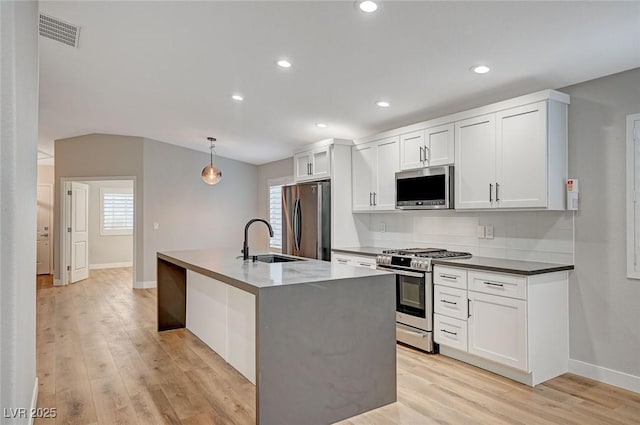 kitchen featuring visible vents, appliances with stainless steel finishes, light wood-style floors, a sink, and an island with sink