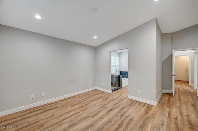 unfurnished living room with lofted ceiling, light wood-style flooring, baseboards, and recessed lighting