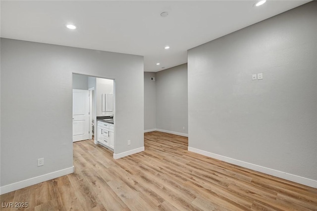 empty room featuring light wood finished floors, recessed lighting, and baseboards