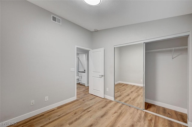 unfurnished bedroom featuring a closet, wood finished floors, visible vents, and baseboards