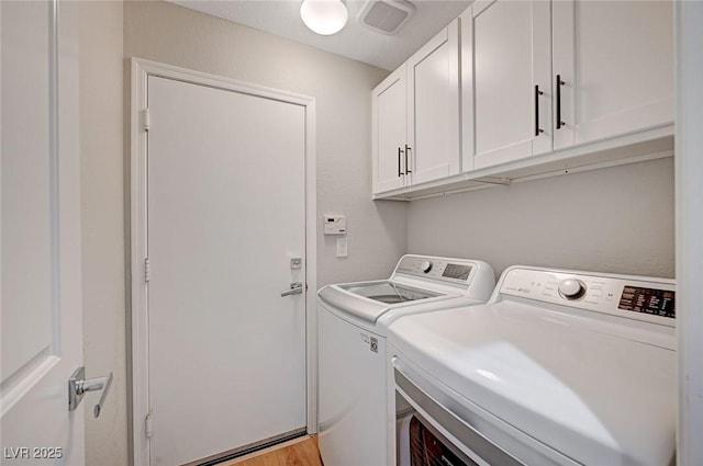 washroom featuring light wood-type flooring, cabinet space, visible vents, and independent washer and dryer