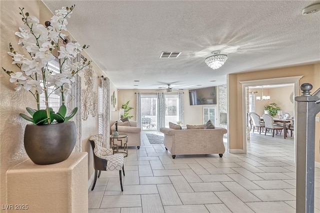 living area featuring a textured ceiling, visible vents, and a ceiling fan