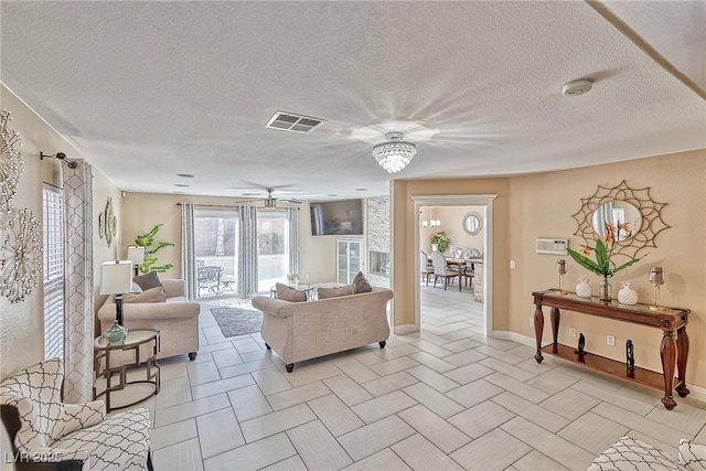 living room featuring visible vents, a textured ceiling, and ceiling fan with notable chandelier