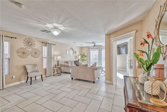 living room with plenty of natural light, visible vents, ceiling fan, and a textured ceiling