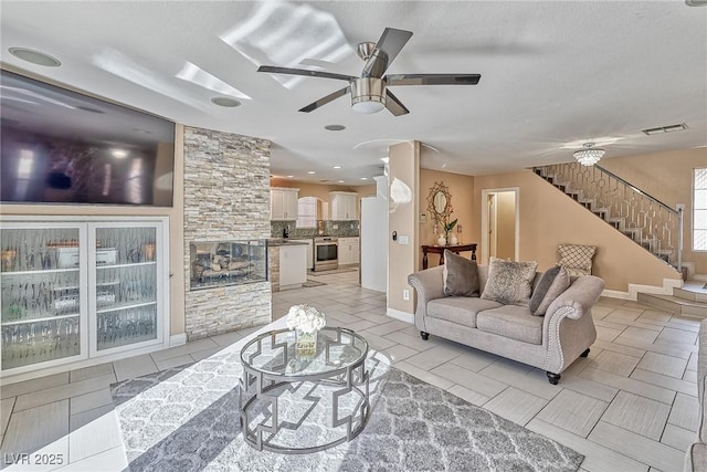 living area featuring stairs, ceiling fan, visible vents, and baseboards