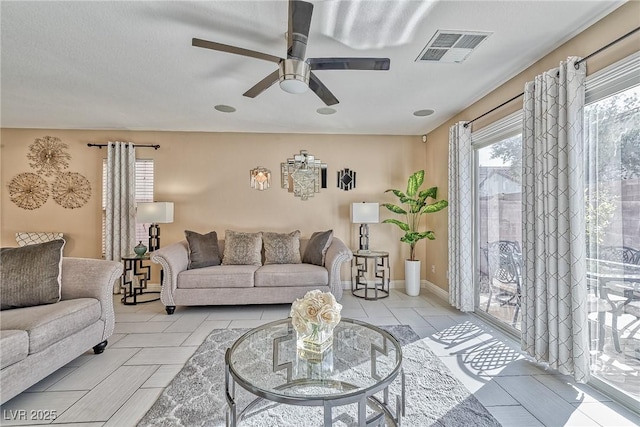 living room with a ceiling fan, visible vents, baseboards, and light tile patterned flooring