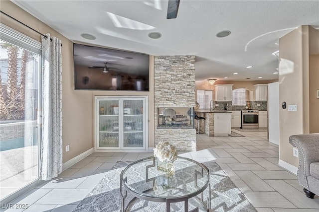 living room with ceiling fan, baseboards, and light tile patterned floors