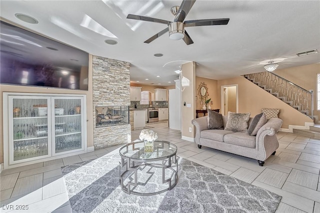 living room with ceiling fan, light tile patterned floors, stairway, and visible vents