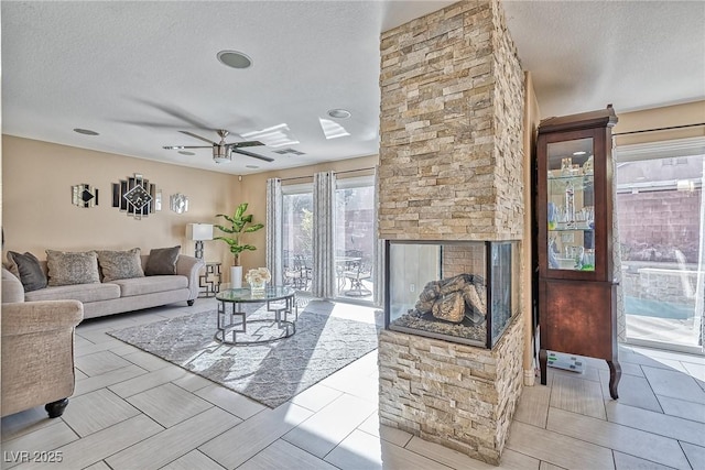 living room with ceiling fan, a textured ceiling, and visible vents