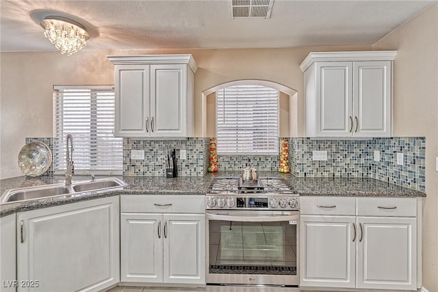 kitchen featuring white cabinetry, stainless steel gas range oven, visible vents, and a sink