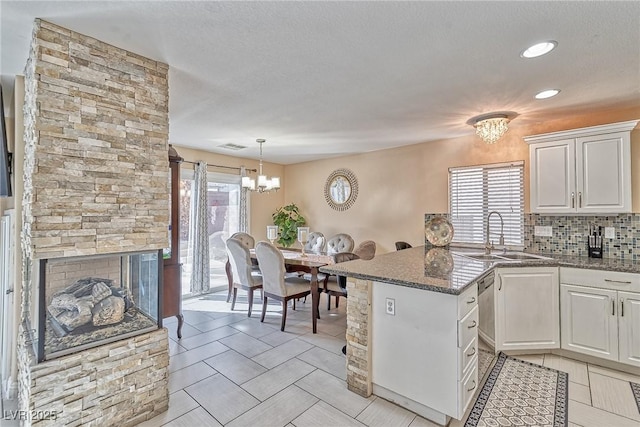 kitchen with backsplash, a healthy amount of sunlight, a sink, a chandelier, and a peninsula