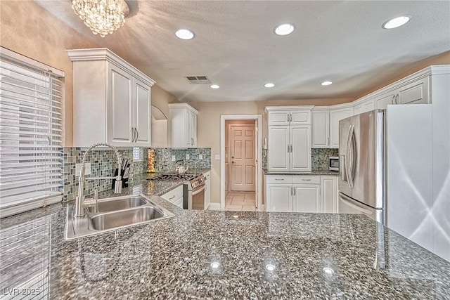 kitchen with stainless steel appliances, backsplash, a sink, and white cabinetry