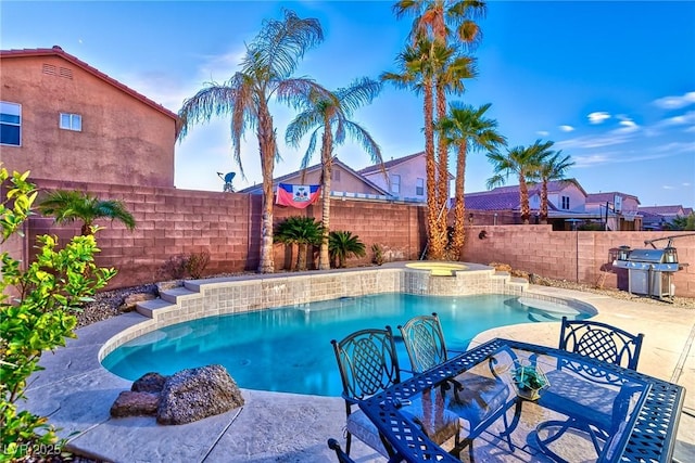 view of pool featuring a patio, grilling area, a fenced backyard, and a pool with connected hot tub