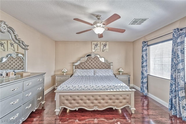 bedroom with a textured ceiling, dark wood-type flooring, visible vents, and baseboards