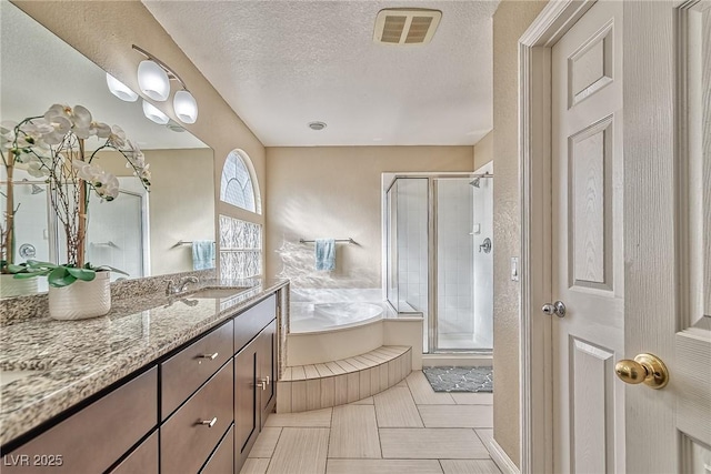 full bathroom featuring visible vents, a shower stall, vanity, a textured ceiling, and a bath