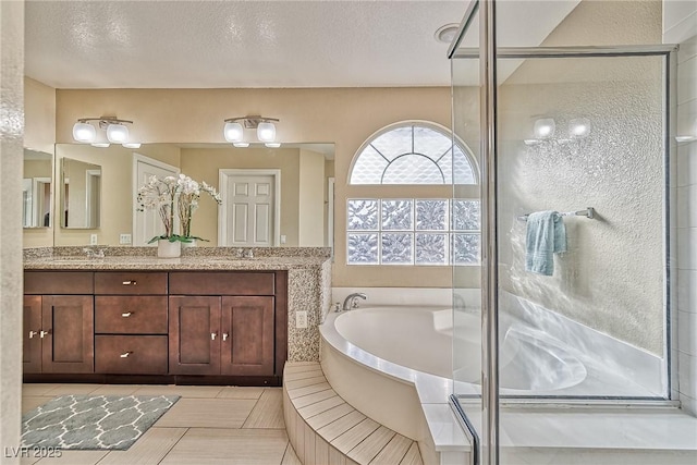 full bath with a stall shower, double vanity, a textured ceiling, and a bath