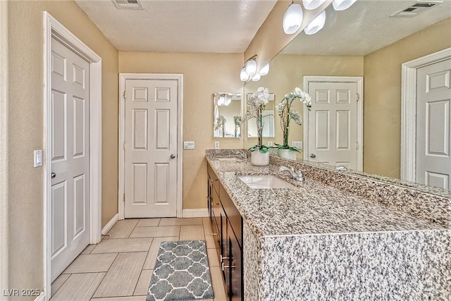 bathroom featuring vanity, visible vents, and baseboards