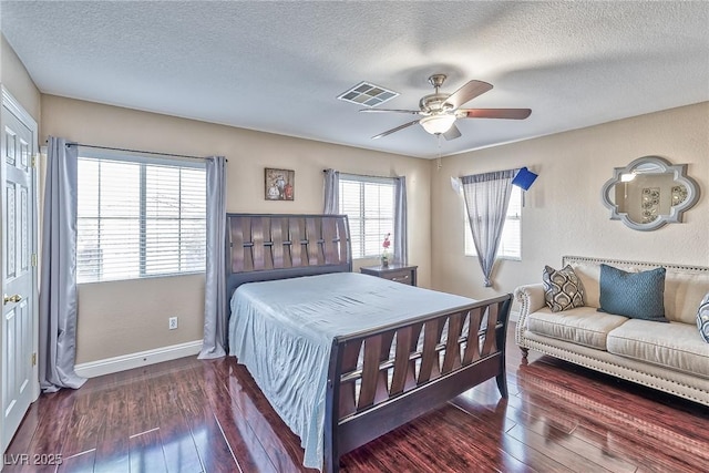 bedroom with ceiling fan, a textured ceiling, visible vents, and hardwood / wood-style floors