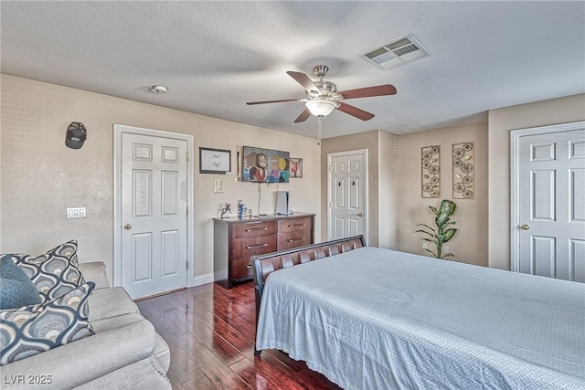 bedroom with dark wood-type flooring, a ceiling fan, visible vents, and baseboards