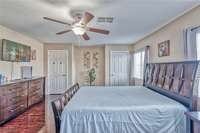 bedroom featuring a ceiling fan, visible vents, and dark wood-type flooring