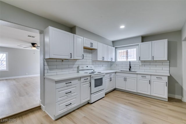 kitchen with a sink, electric range, a wealth of natural light, and light countertops