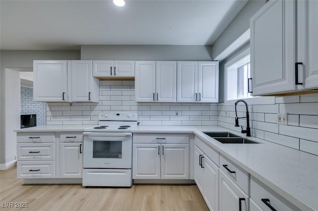 kitchen with white electric range, white cabinetry, light wood finished floors, and a sink