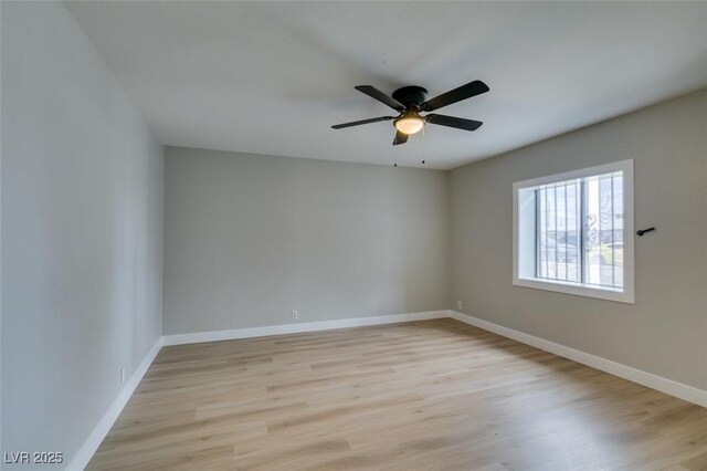 spare room with ceiling fan, light wood-type flooring, and baseboards