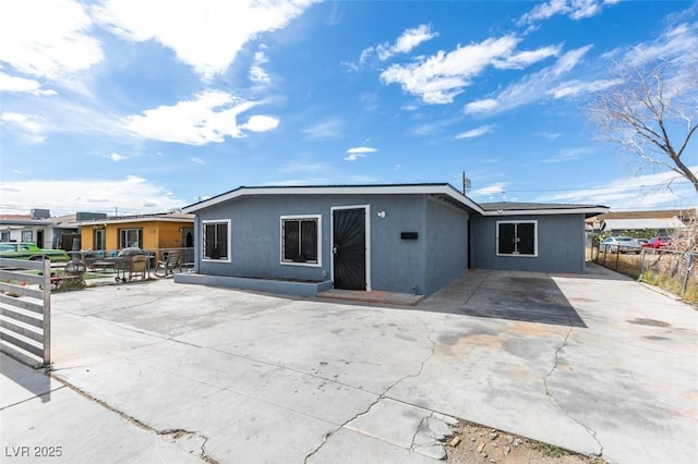 rear view of property featuring a patio area, fence, and stucco siding