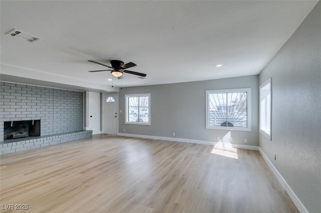 unfurnished living room featuring visible vents, a brick fireplace, baseboards, and wood finished floors