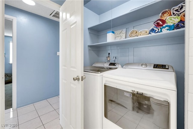 laundry area with laundry area, visible vents, washing machine and clothes dryer, and light tile patterned floors