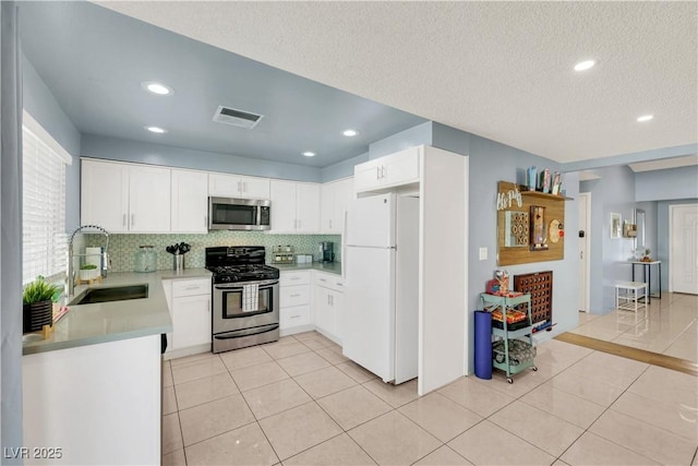 kitchen with appliances with stainless steel finishes, visible vents, a sink, and light tile patterned floors