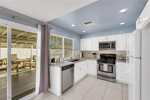 kitchen with tasteful backsplash, visible vents, stainless steel appliances, light countertops, and a sink