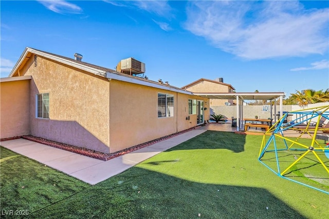 rear view of property featuring a yard, fence, a patio, and stucco siding