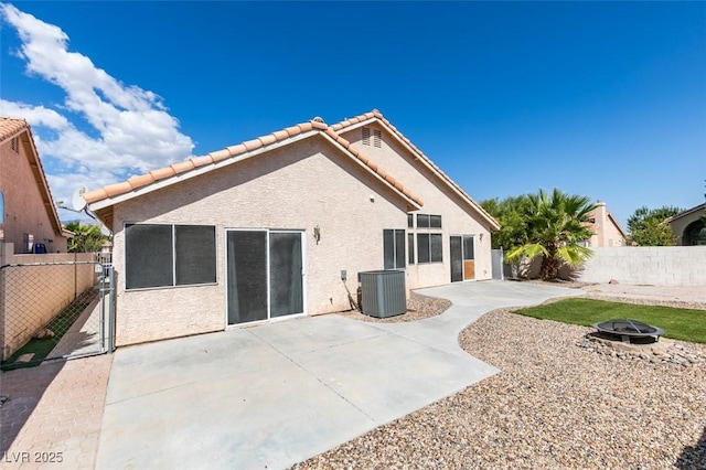 rear view of house featuring central AC unit, an outdoor fire pit, a fenced backyard, stucco siding, and a patio area