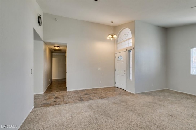 foyer entrance with a towering ceiling, a wealth of natural light, a chandelier, and carpet flooring