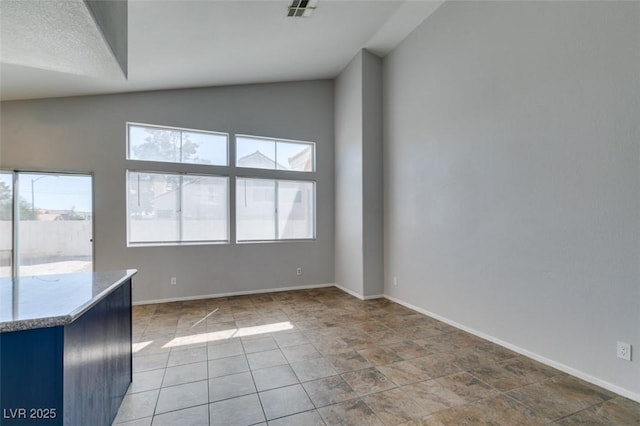 interior space with vaulted ceiling, baseboards, visible vents, and a healthy amount of sunlight