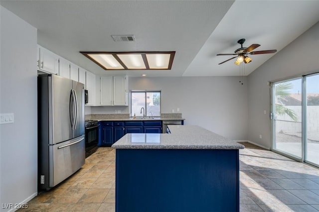 kitchen with blue cabinetry, stainless steel appliances, a wealth of natural light, visible vents, and a sink