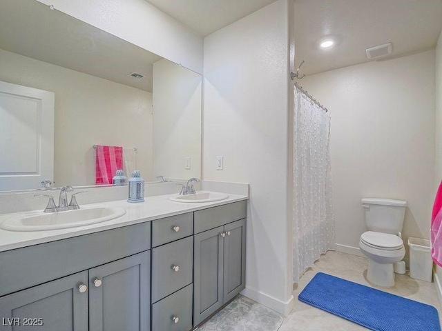 bathroom featuring double vanity, visible vents, toilet, and a sink