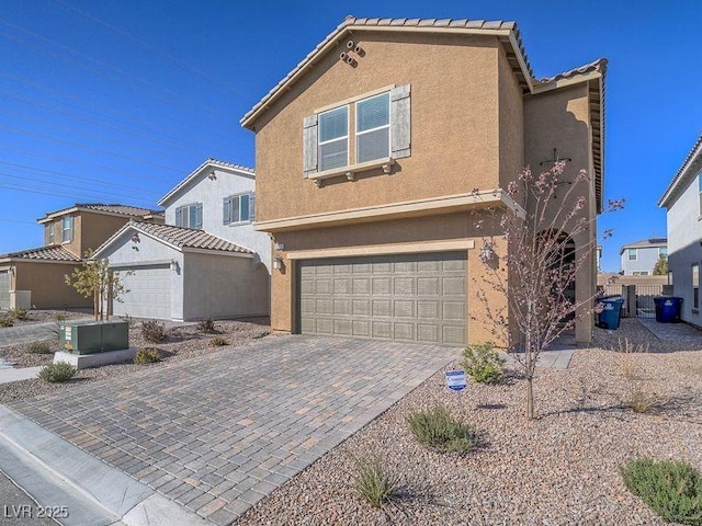 view of front of home with stucco siding, a tiled roof, decorative driveway, and a garage