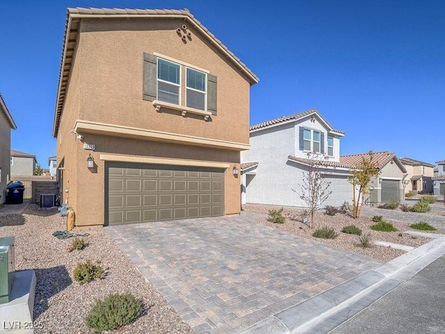 view of front of property with decorative driveway, a tiled roof, an attached garage, and stucco siding