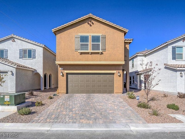 mediterranean / spanish-style house with a tile roof, decorative driveway, a garage, and stucco siding