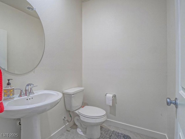 half bathroom featuring baseboards and toilet