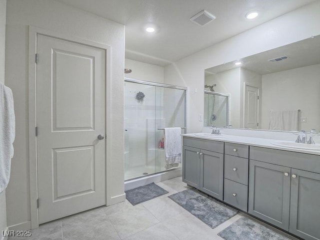 full bathroom featuring double vanity, visible vents, a shower stall, and a sink