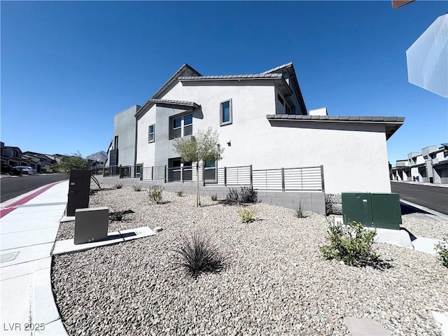 view of side of home with stucco siding and fence